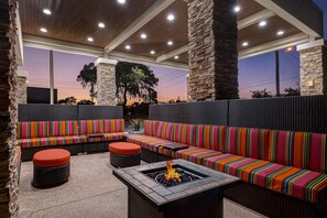 An outdoor seating area with a fire pit, stone pillars, and a view of the sunset. - Home2 Suites by Hilton Gulf Breeze Pensacola Area (Gulf Breeze)