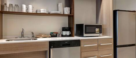 A modern kitchen with a dishwasher, a refrigerator, a microwave, and a coffee maker.