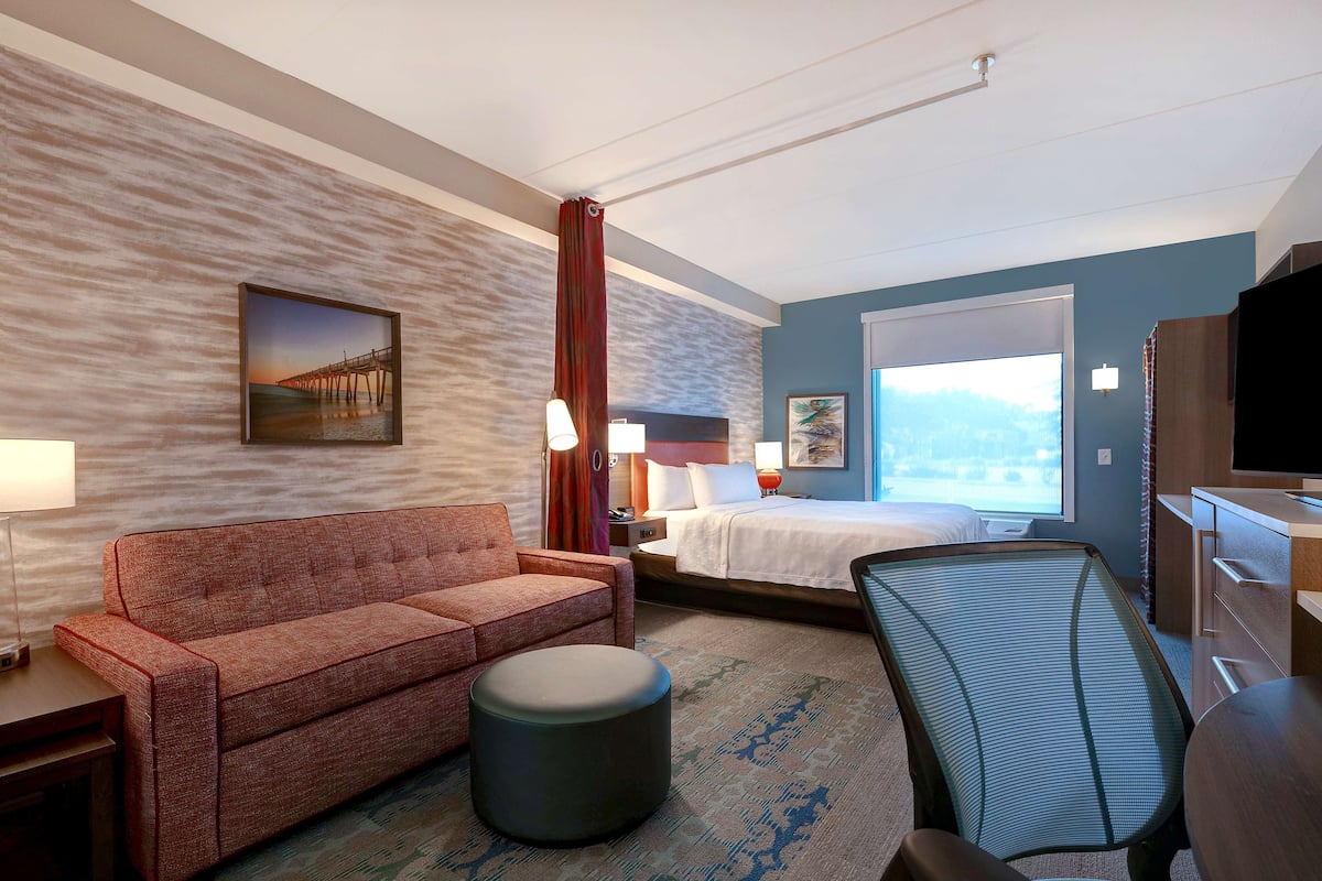 Ett hotellrum med en soffa, en säng, ett skrivbord, en stol och en TV.