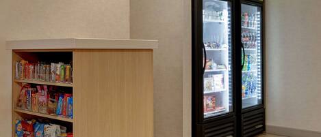 Uma área de loja com balcões refrigerados e prateleiras repletas de diversos produtos alimentícios.