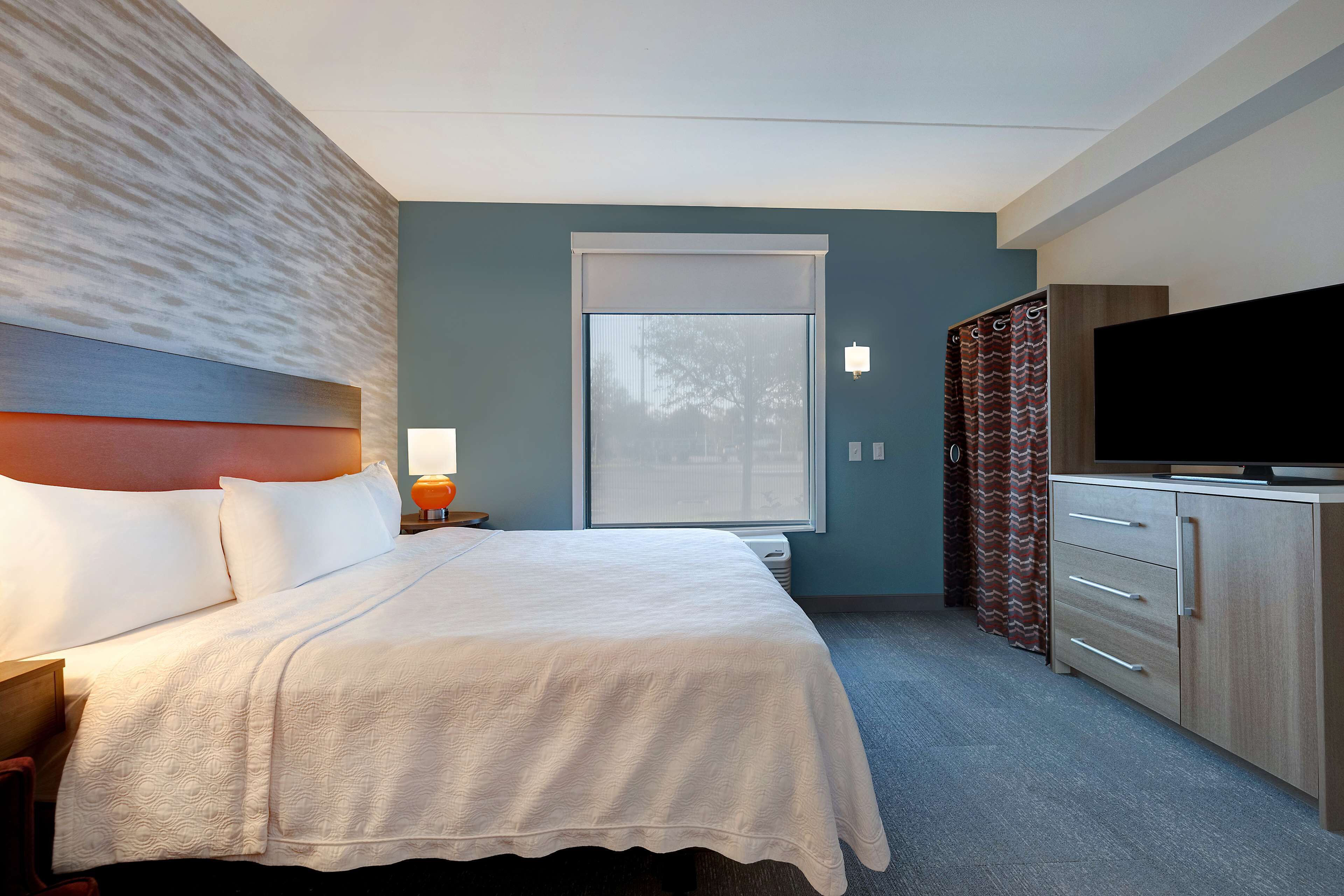 Una habitación de hotel con cama, televisión, escritorio y ventana.