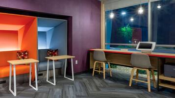 A modern office space with a desk, two chairs, a small table, and a window with a view of the outside.