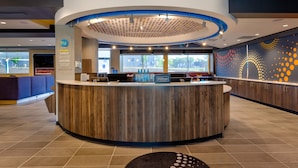 Zona de recepción de un hotel con un mostrador circular, un letrero de Hilton Honors y una pared con un diseño de puntos.