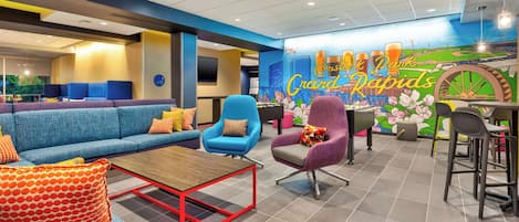 A modern lounge area with blue and purple seating, a wooden coffee table, and a mural of a baseball field.