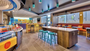 Interior de restaurante moderno con barra central, diferentes disposiciones de asientos y un mostrador con bebidas.