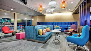 Un área de estar moderna con un sofá azul, sillas coloridas y un sillón colgante.