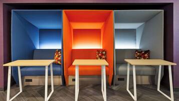 A modern room with a blue and orange seating area, two white tables, and patterned cushions.