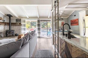 A cozy living room with a fireplace, a sofa, and a kitchen area with a sink and counter.