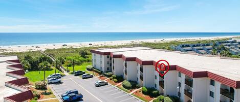 A hotel with a parking lot, a beach view, and a red location marker.