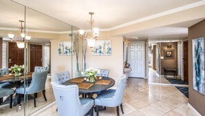 A dining area with a round table, blue upholstered chairs, a chandelier, and artwork on the walls. - Mountain Views and walk out to Silverado golf course and greenbelt by Old Town (Scottsdale)