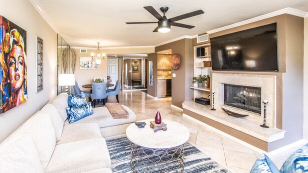A spacious living room with a fireplace, a ceiling fan, and a large TV. - Mountain Views and walk out to Silverado golf course and greenbelt by Old Town (Scottsdale)