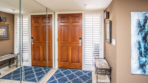A hallway with a wooden door, a bench, a glass door, and a painting on the wall. - Mountain Views and walk out to Silverado golf course and greenbelt by Old Town (Scottsdale)