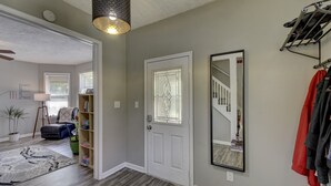 A hallway with a white door, a mirror, and a coat rack. - Charm Near Omaha Downtown: 4-Bed, 2-Bath Gem (Omaha)