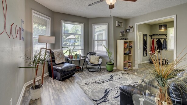 A spacious living room with a ceiling fan, a leather sofa, a coffee table, and a bookshelf. - Charm Near Omaha Downtown: 4-Bed, 2-Bath Gem (Omaha)