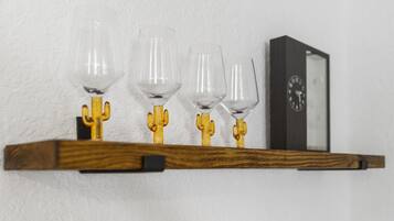 Una estantería de madera con cuatro copas de vino y un reloj.
