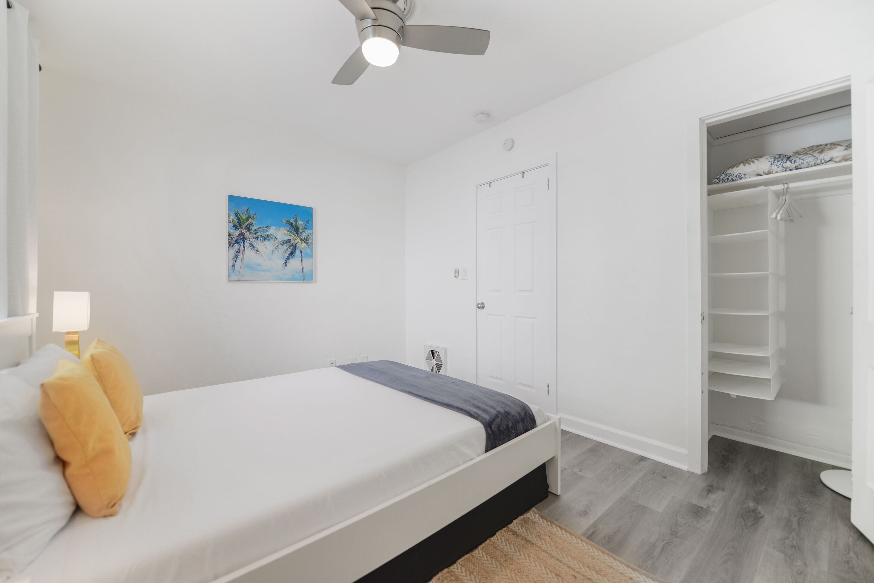 Une chambre à coucher avec un lit, un ventilateur de plafond, une porte et un placard.