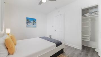 A bedroom with a bed, a ceiling fan, a door, and a closet.