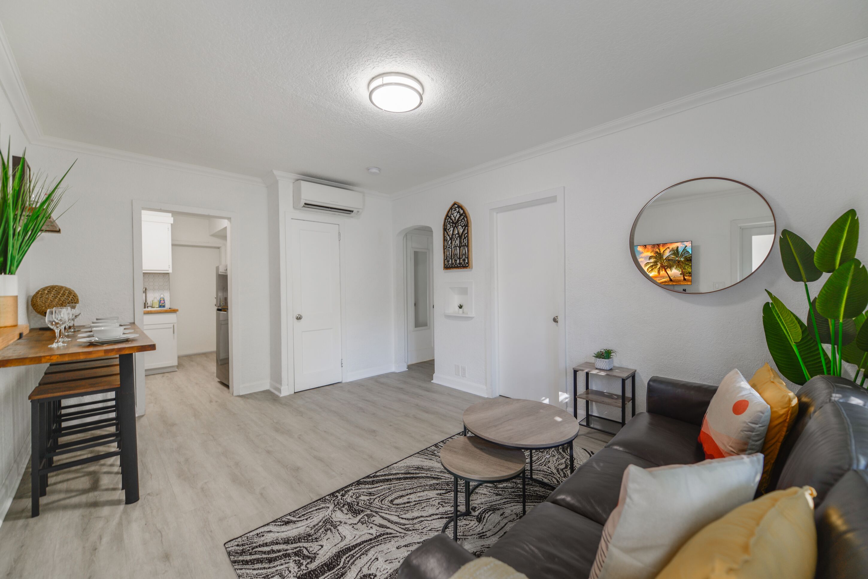 Een moderne woonkamer met een bank, salontafel en een eethoek met een tafel gedekt voor vier personen.