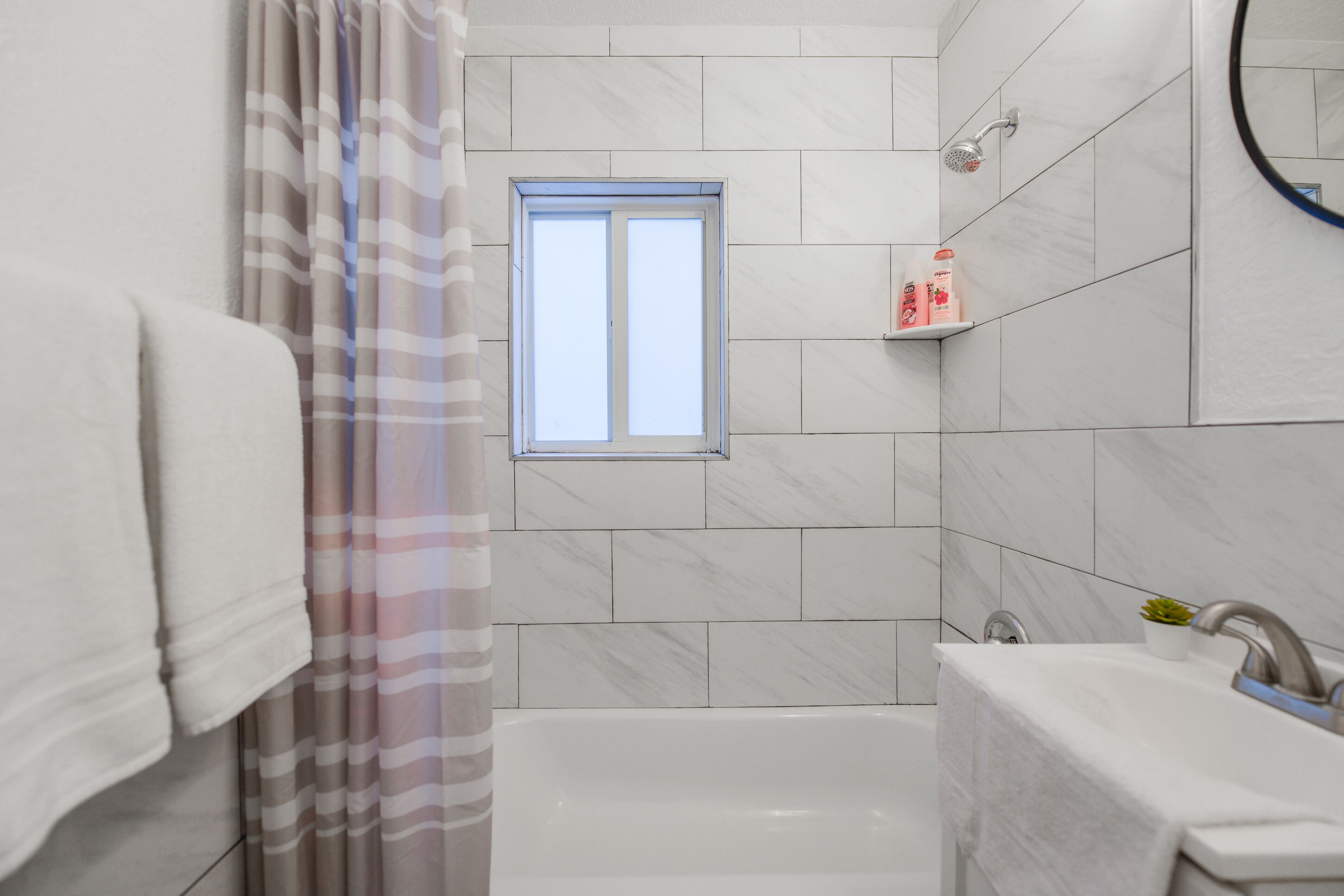 Un baño moderno con bañera, ventana y ducha.