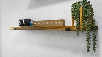 A wooden shelf with a motivational sign, a mug, and a hanging plant against a textured wall.