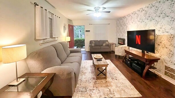 Een woonkamer met een bank, salontafel, televisie en een plafondventilator.