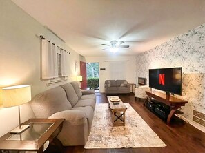 A living room with a sofa, coffee table, TV, and a ceiling fan.