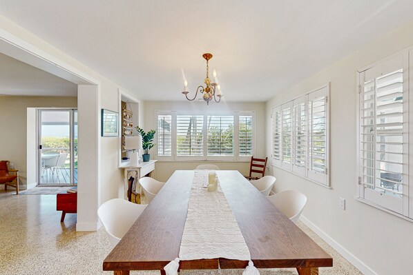 Enjoy meals in this elegant dining area with a long table, chandelier, and large windows.