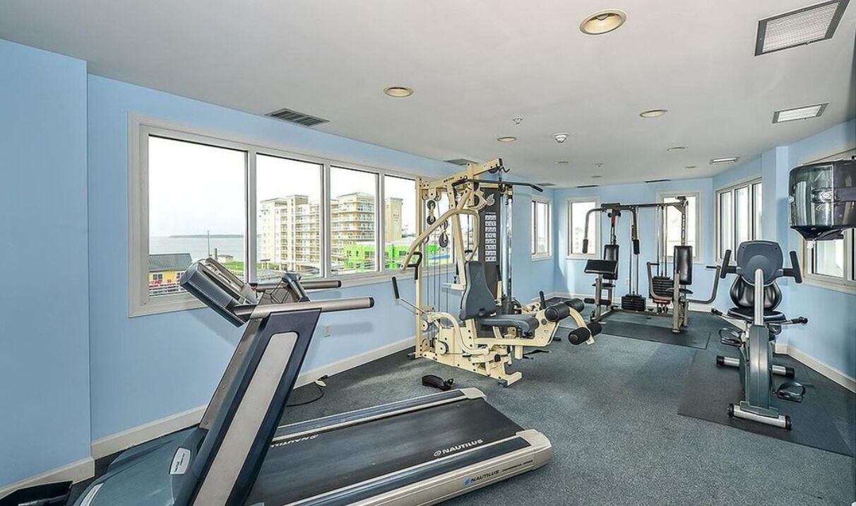 A gym with Nautilus equipment, large windows, and a view of buildings.