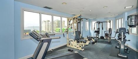 A gym with Nautilus equipment, large windows, and a view of buildings.