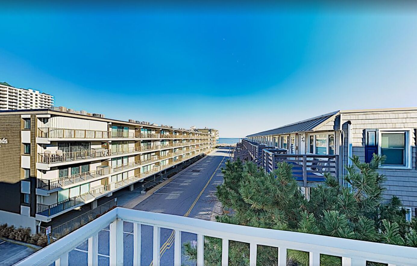A modern hotel with multiple floors, balconies, and a view of the ocean.