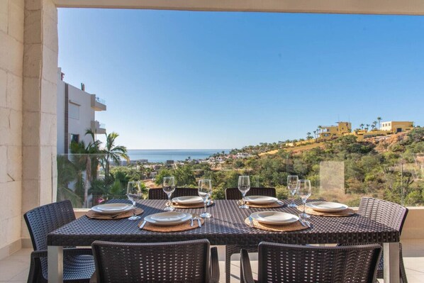 A table set for six with a view of the sea and a hillside.
