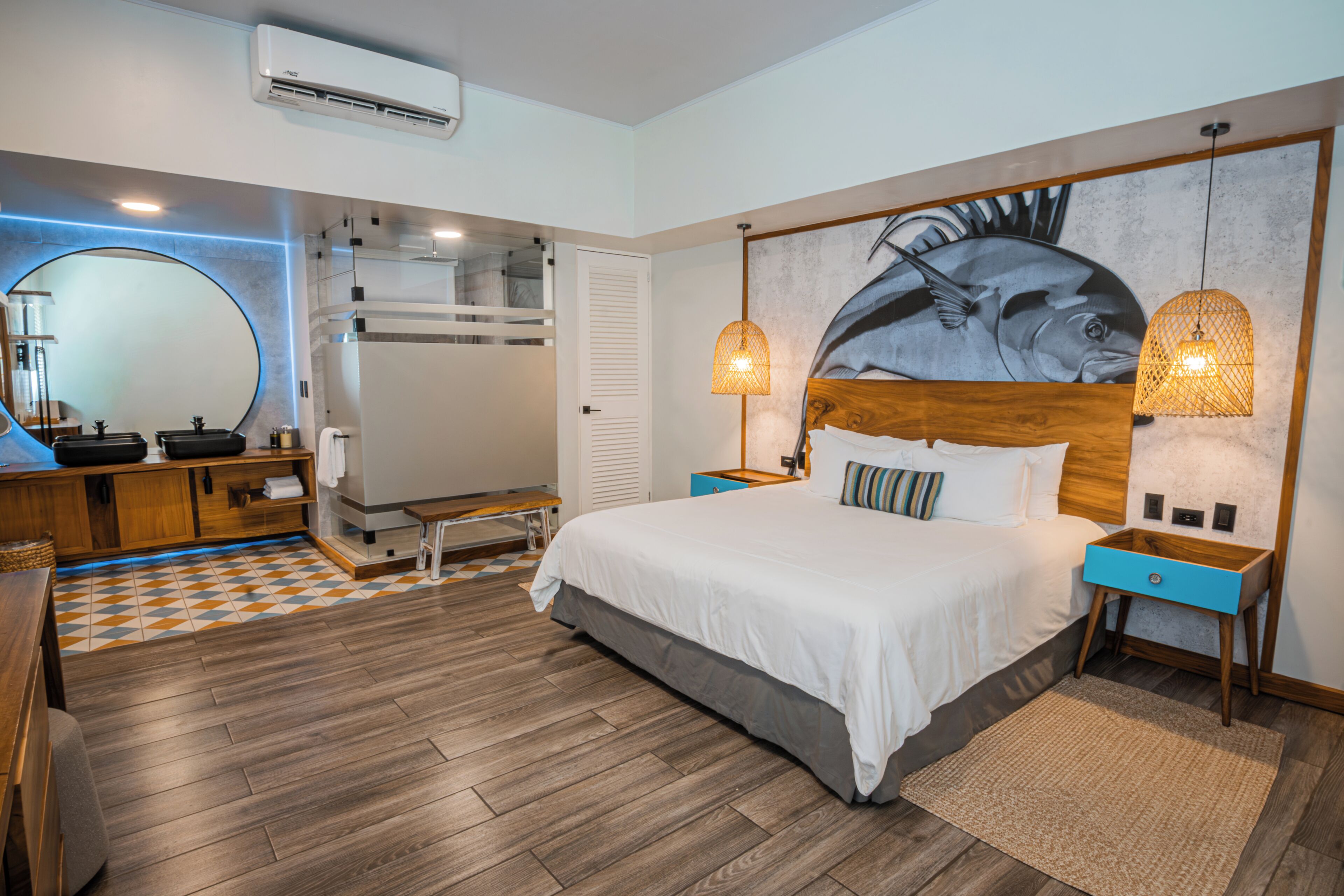 A bedroom with a bed, bedside tables, a mirror, a wall-mounted heater, and a large fish mural.
