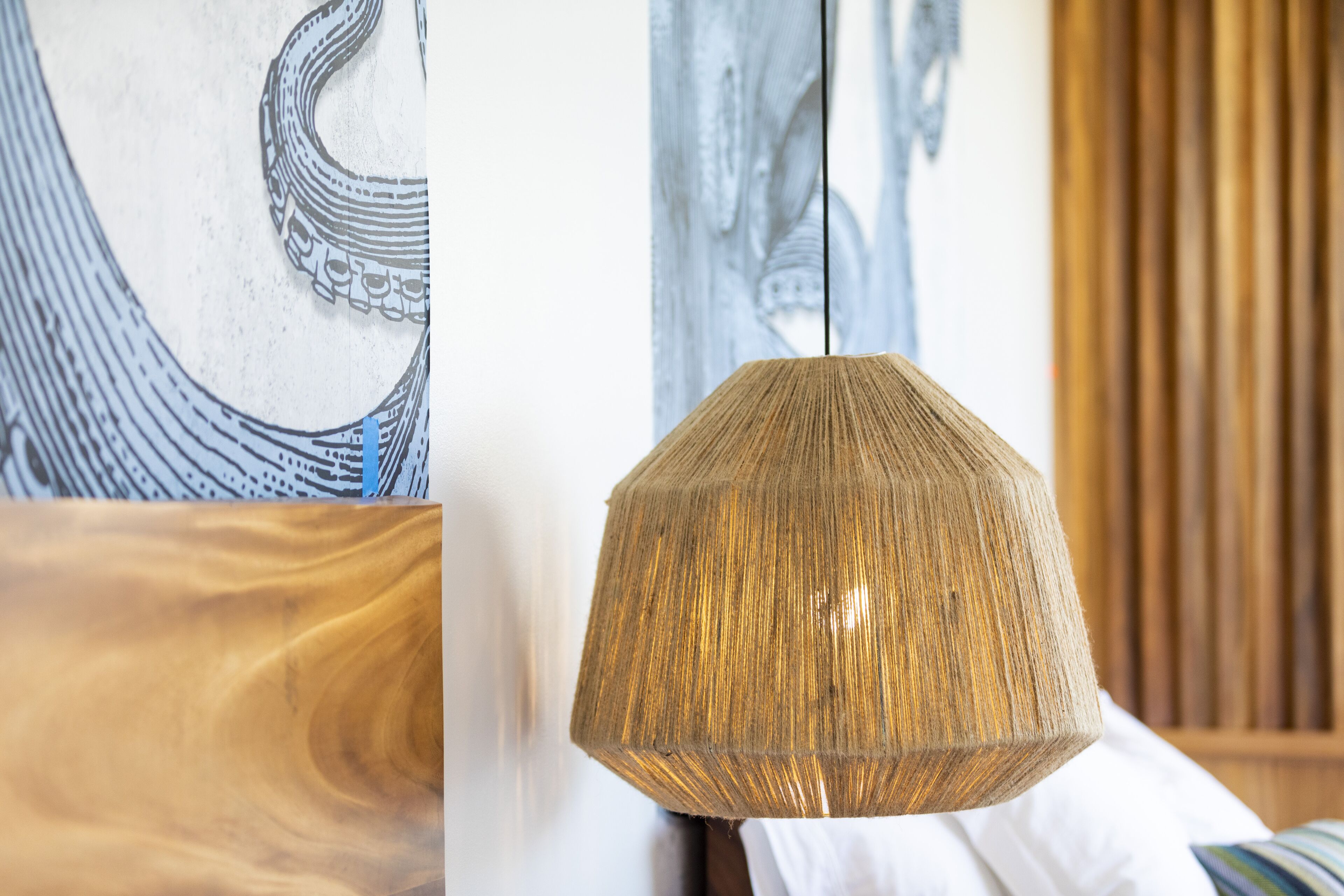 A room with a hanging lamp, wooden furniture, and artwork on the walls.