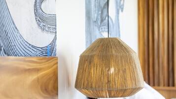 Um quarto com luminária pendente, móveis de madeira e obras de arte nas paredes.