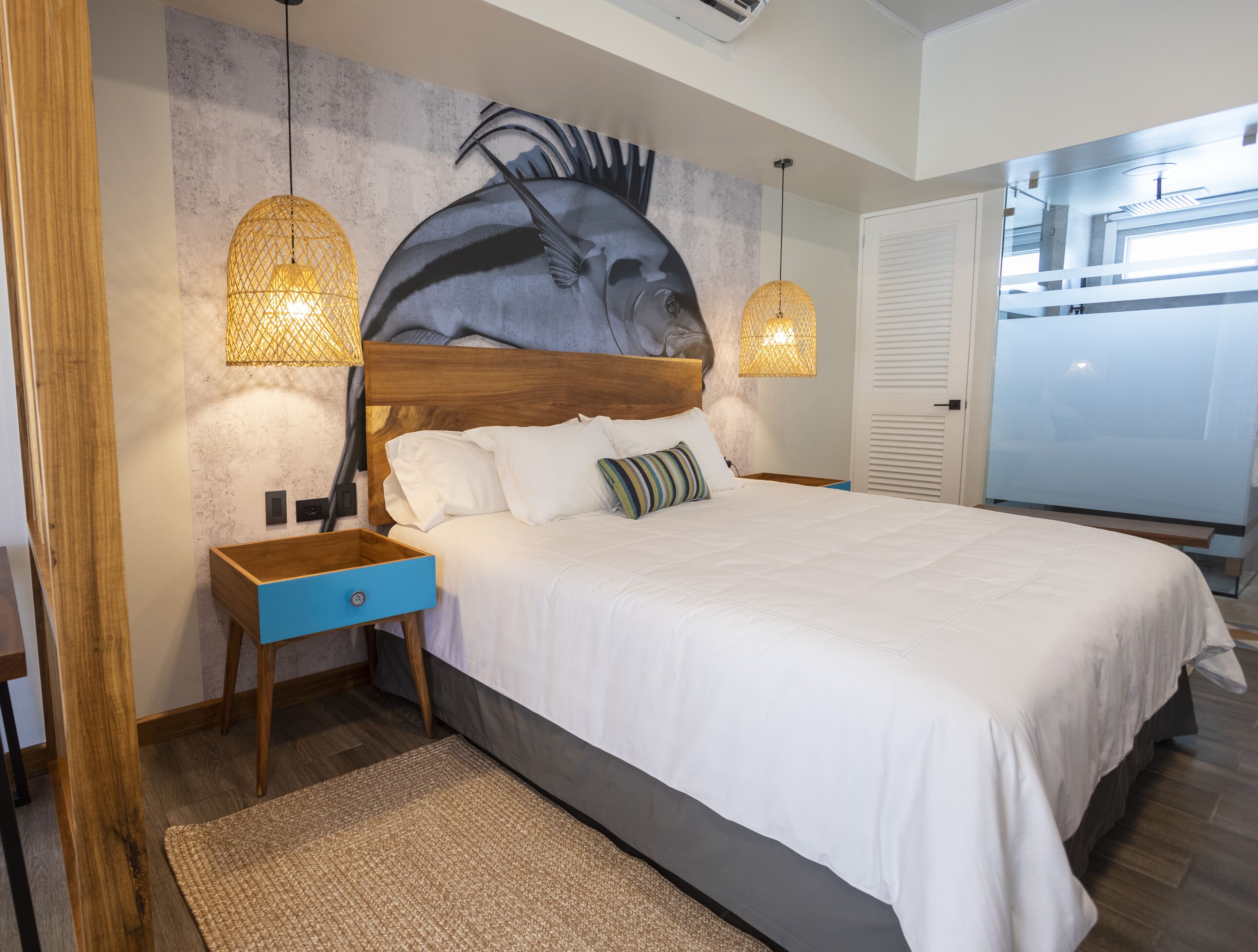 A modern bedroom with a large bed, wooden nightstand, two wall-mounted lamps, and a textured wall mural.