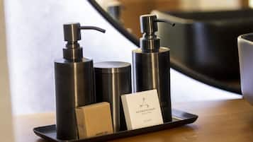 A tray with two black dispensers and a soap bar labeled "Aromatherapy Associates Soap" on a wooden surface.