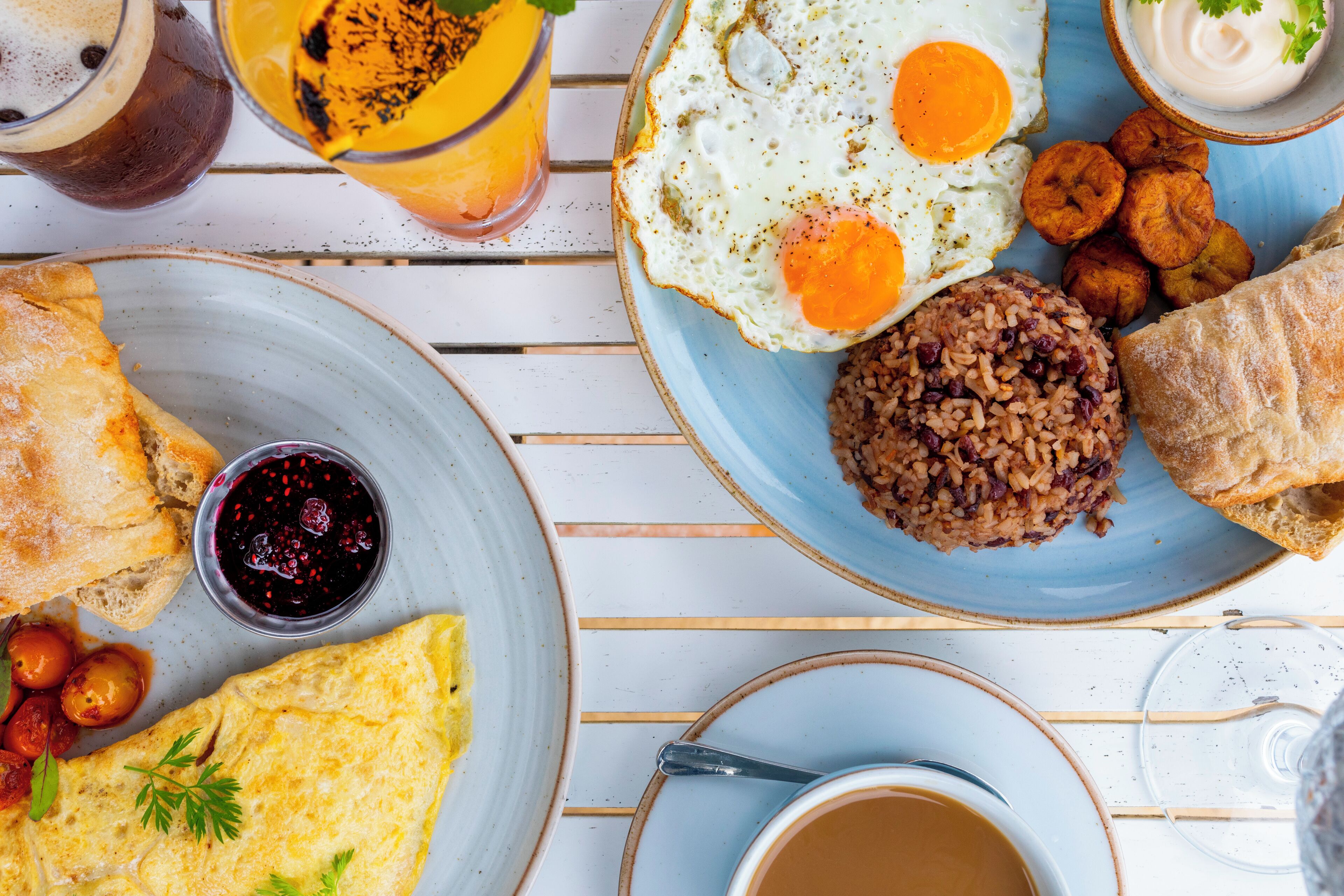 Un petit-déjeuner composé d’œufs, de pain grillé et d’une tasse de café, le tout disposé sur une table en bois blanche.