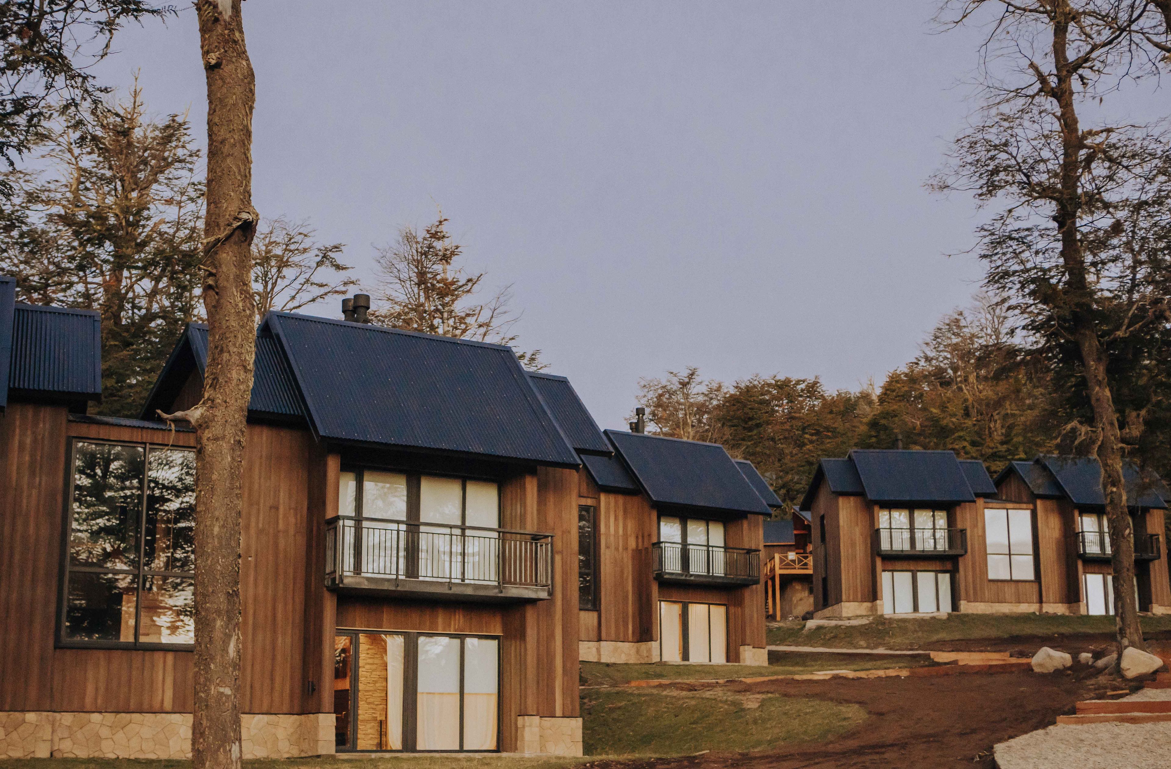 Una hilera de cabañas de madera con techos oscuros, ventanas amplias y balcones.
