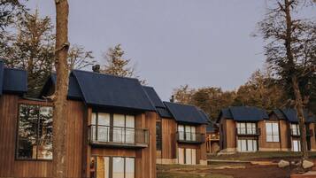 Una hilera de cabañas de madera con techos oscuros, ventanas amplias y balcones.