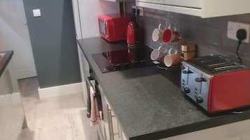 A modern kitchen with a black countertop, red toaster, and a coffee maker.