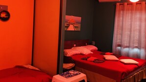 Een kamer met twee bedden, een klein krukje, een plafondventilator en een foto aan de muur.