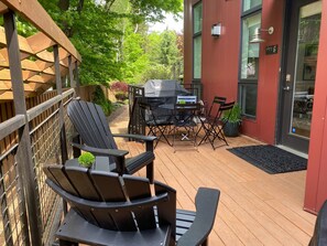 Une terrasse avec des meubles d’extérieur, un barbecue et un bâtiment rouge doté de grandes fenêtres.