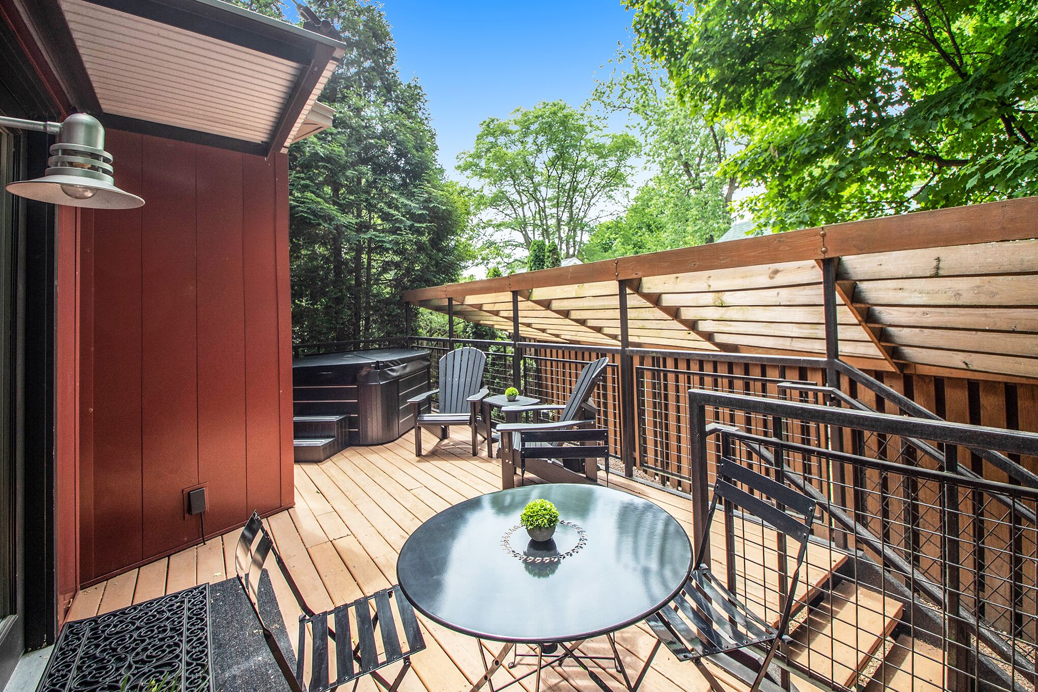 A wooden deck with outdoor furniture, including a table and chairs, and a pergola structure.