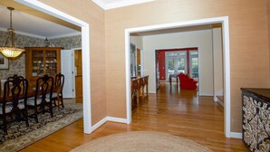 Una sala de estar amplia con pisos de madera, un comedor con mesa y sillas de madera, y un sofá rojo.