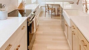 Una cocina moderna con armarios blancos, una isla central y una zona de comedor.