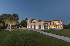 Una casa moderna de dos pisos con entrada de vehículos y un árbol en primer plano.