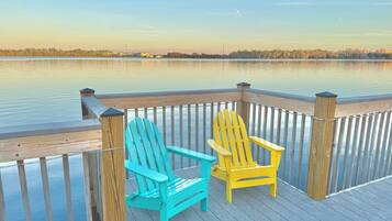 Een houten terras met twee Adirondack-stoelen uitkijkend op een rustig meer.