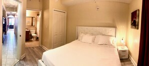 A bedroom with a large bed, a nightstand, and a wall-mounted lamp. - Lakefront Condo · Disney Fireworks, Sunrise Views · Heated Pools · 2 Full Baths (Orlando)