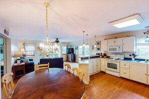 Enjoy meals in the well-appointed kitchen and dining area, featuring an oven, microwave, and wooden table.