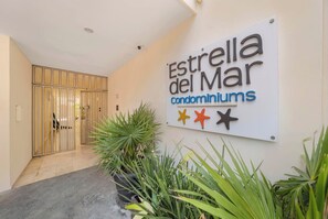Une enseigne indiquant « Résidences Estrella del Mar », avec une grille en métal et des plantes en pot au premier plan.